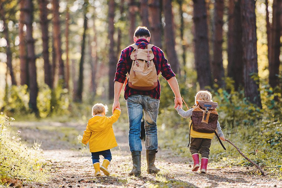 Employee Benefits - A Rear View of a Father With His Toddler Children Walking in an Autumn Forest